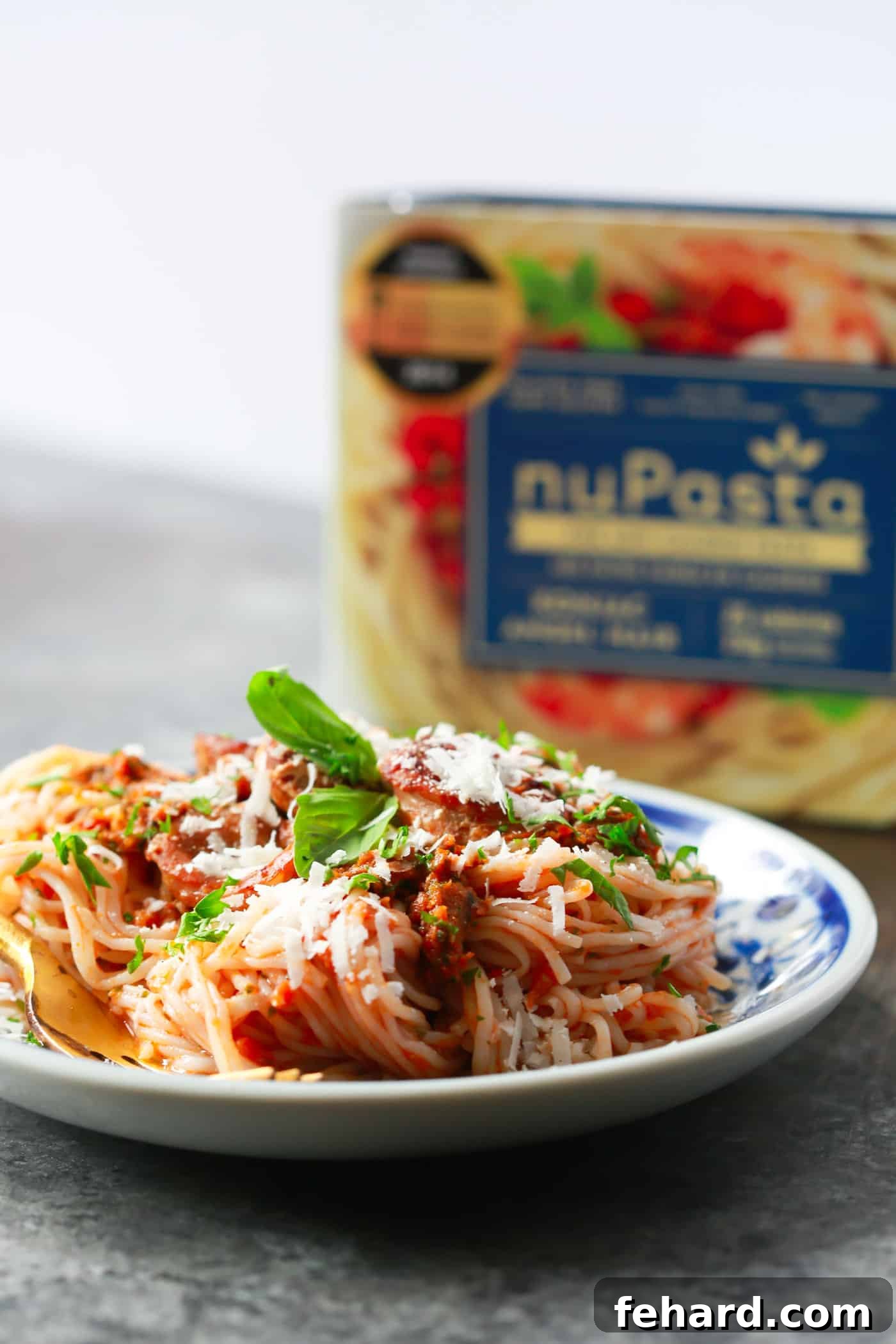 Flavorful Pesto Pasta with Low-Carb NuPasta A close-up of a serving of Italian Sausage Sun-dried Tomato Pesto Pasta, highlighting the beautifully coated nuPasta strands and chunks of savory Italian sausage, promising a deeply satisfying experience.
