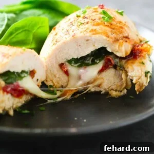 Close up of a Sun Dried Tomato, Spinach and Cheese Stuffed Chicken on a black plate, ready to be enjoyed.