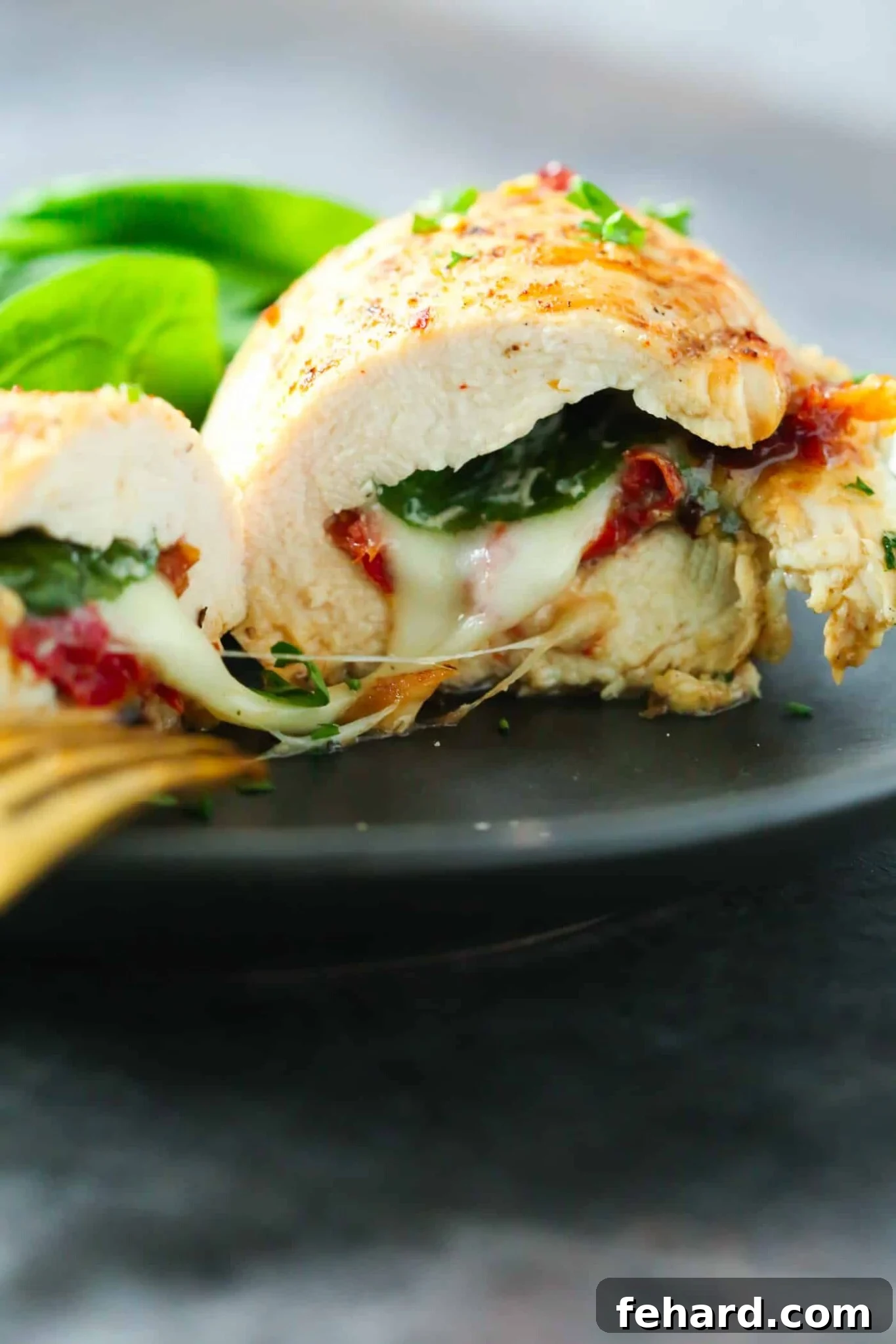 Spinach stuffed chicken breast cut in half on a plate, revealing its creamy filling and golden crust.