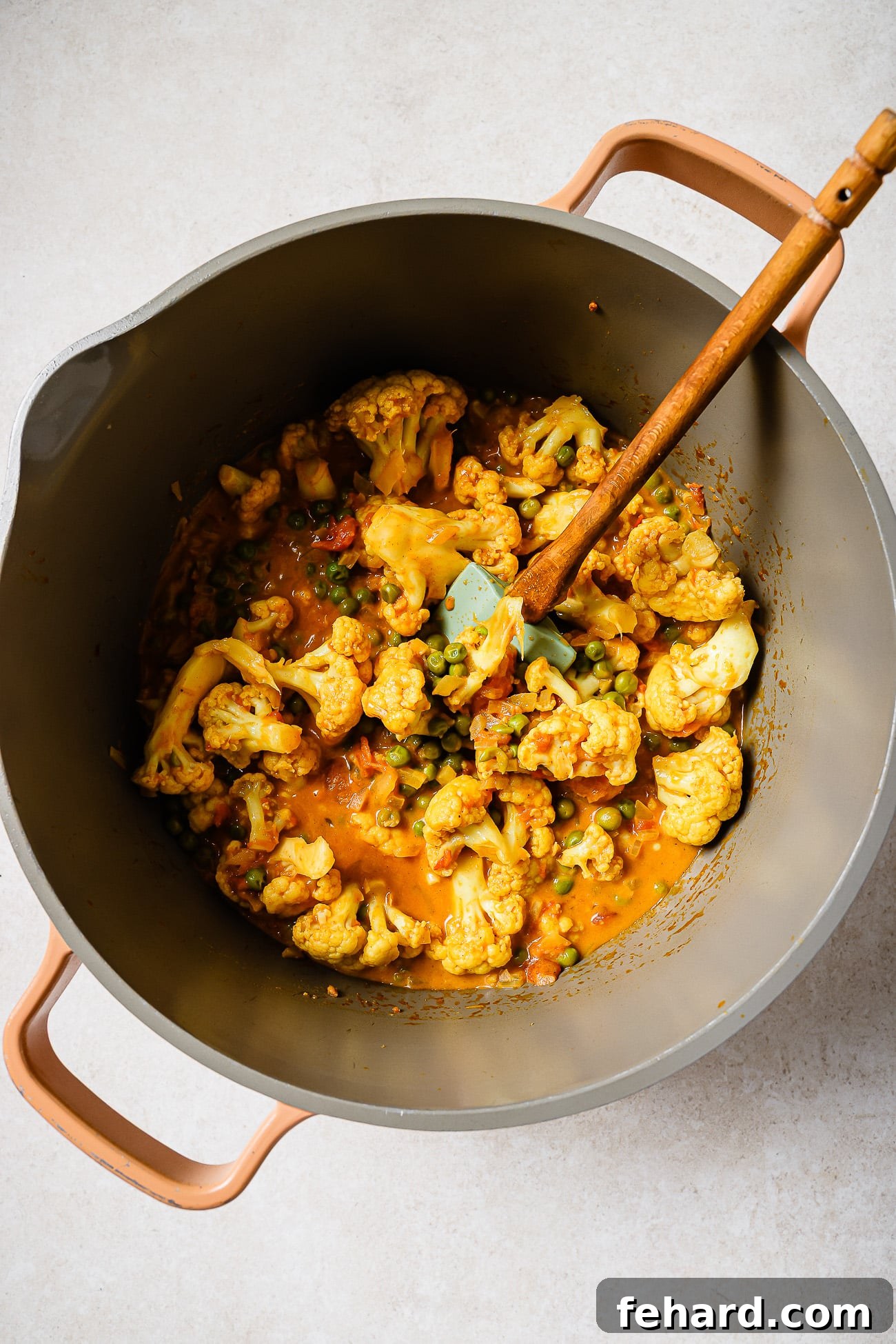 Cauliflower and peas in a pot with coconut curry sauce.