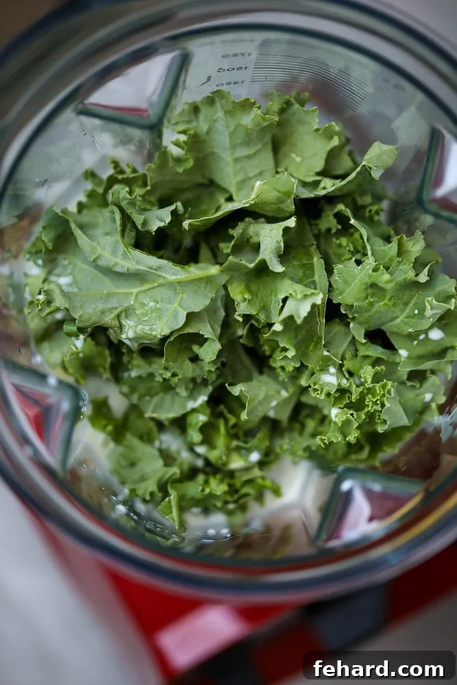 Green Smoothie Recipe Preparation A blender filled with creamy coconut milk and vibrant fresh kale, ready to be transformed into a healthy green smoothie.