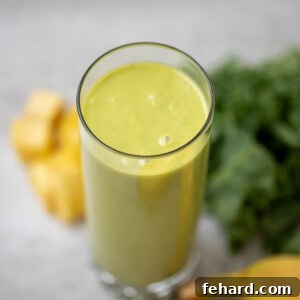Glass of Tropical Kale Smoothie with pineapple and banana in the background, a perfect healthy drink