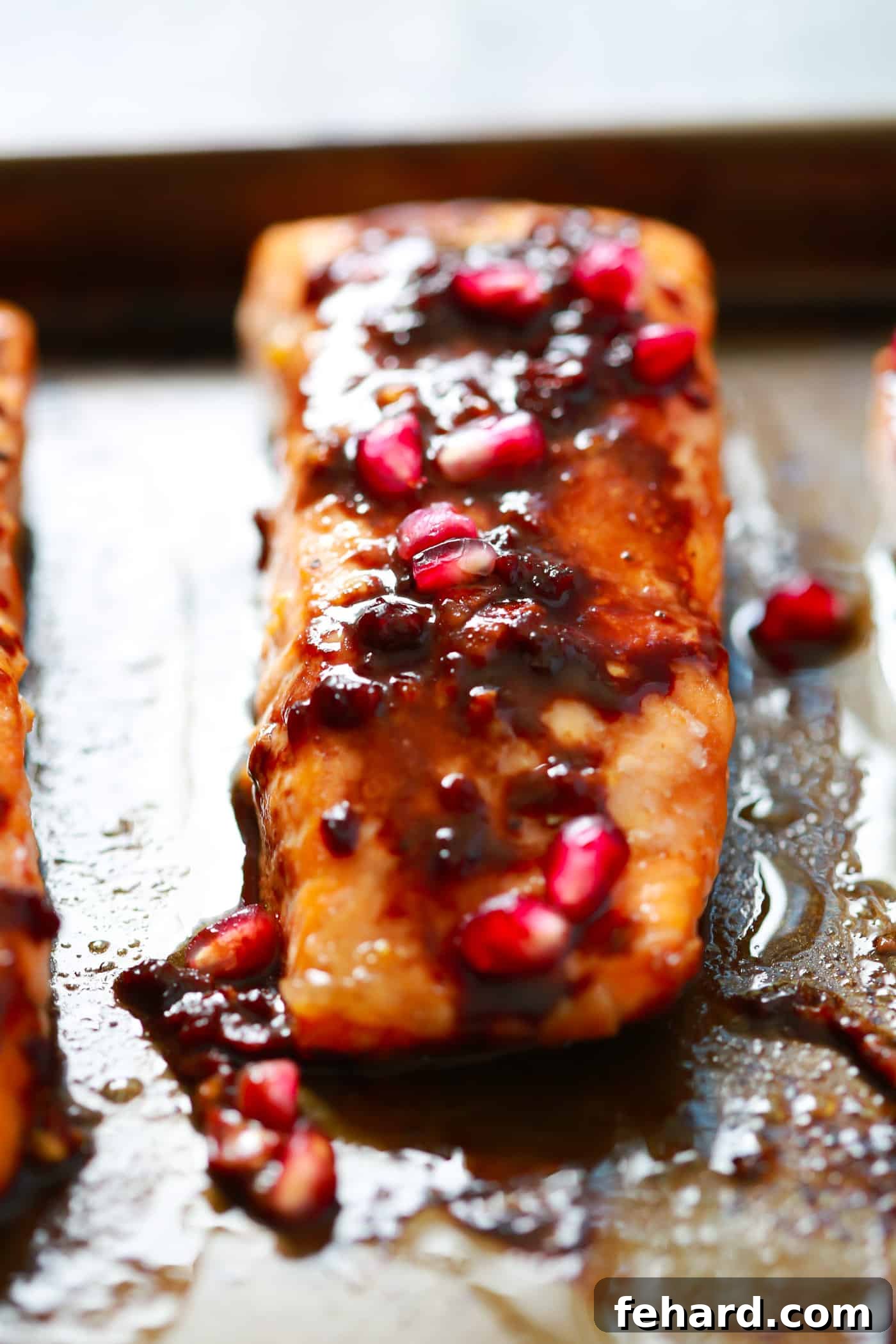A healthy and flavorful Pomegranate Glazed Salmon, perfect for a quick dinner. A close-up of a single pomegranate glazed salmon fillet on a plate, garnished with fresh pomegranate arils and herbs.