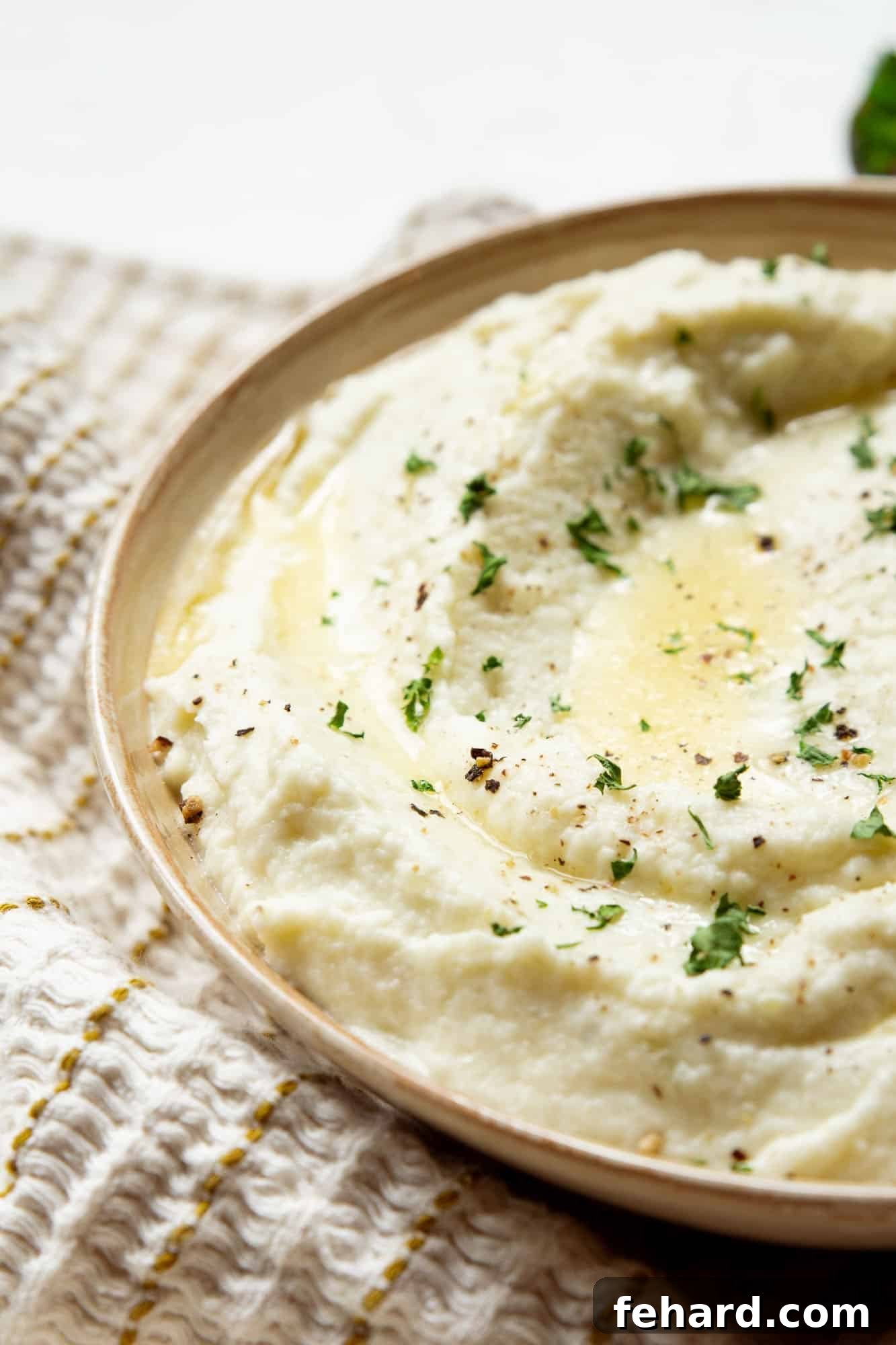 Close up of a beautifully garnished bowl of mashed cauliflower, ready to be served.