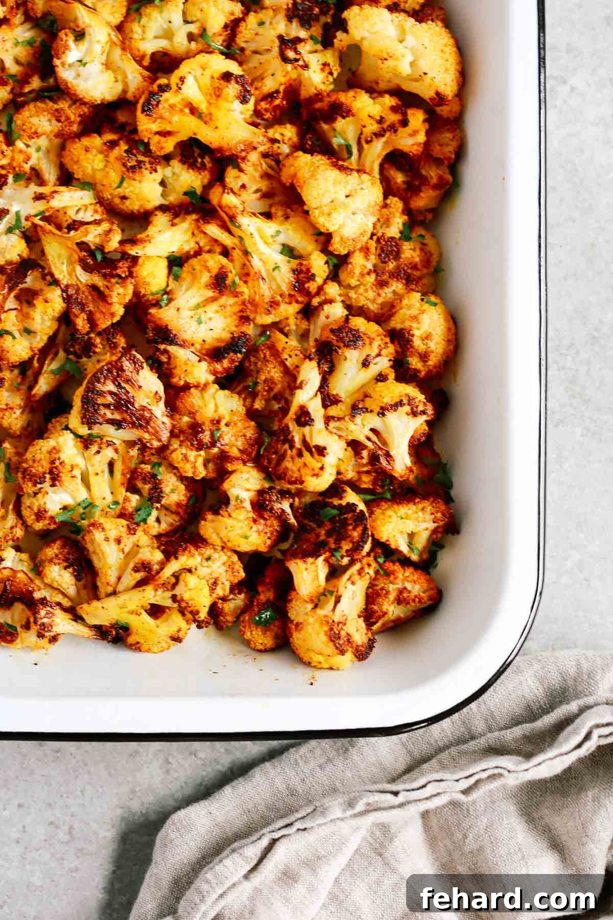 Bowl with a generous serving of freshly roasted cauliflower, garnished with green herbs