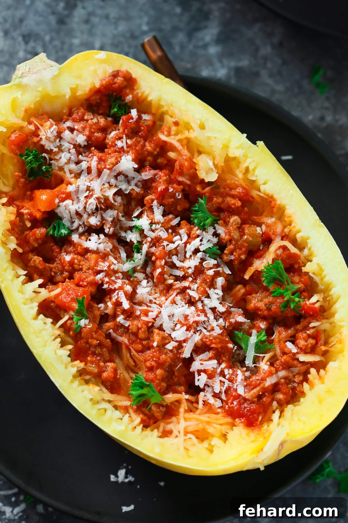 Close-up of Bolognese Stuffed Spaghetti Squash halves, garnished with fresh herbs and parmesan