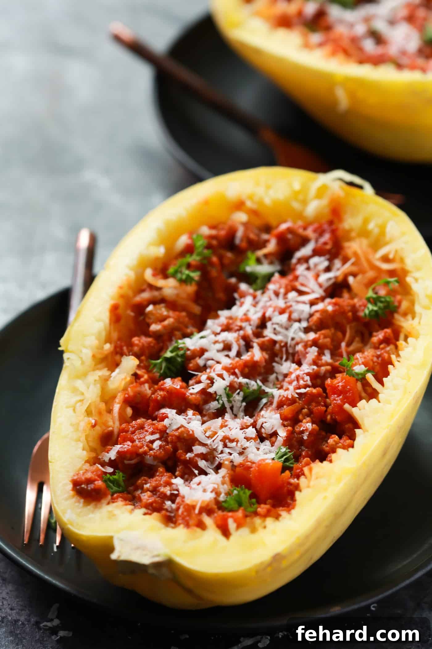 Two halves of spaghetti squash stuffed generously with rich bolognese sauce, ready to be served