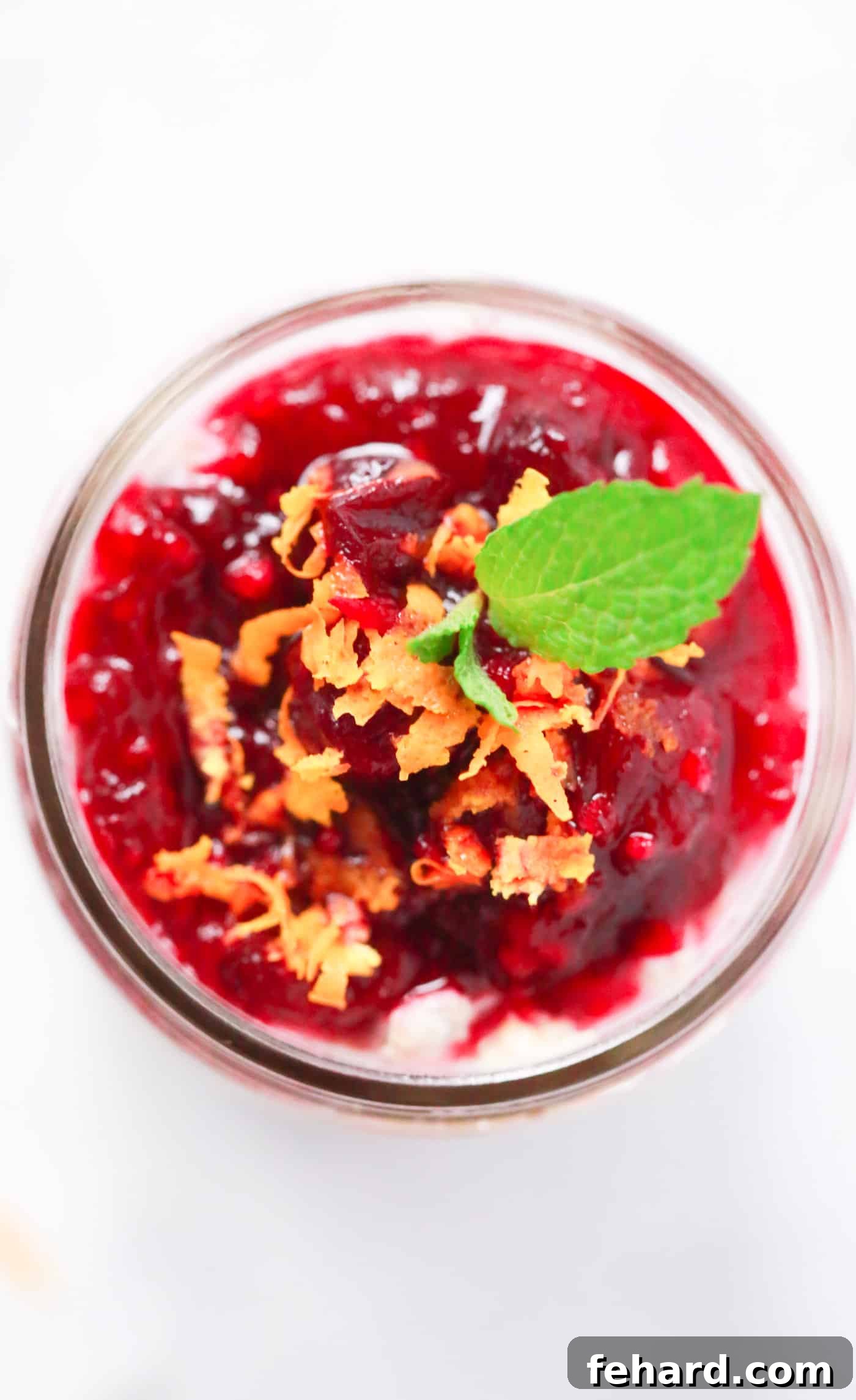 Close-up shot of Cranberry Oatmeal in a glass jar, layered with cranberry sauce