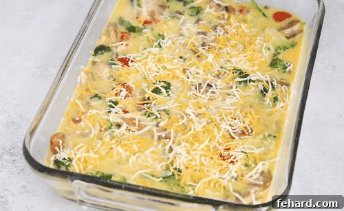 overhead view of raw veggie casserole with egg mixture and cheese