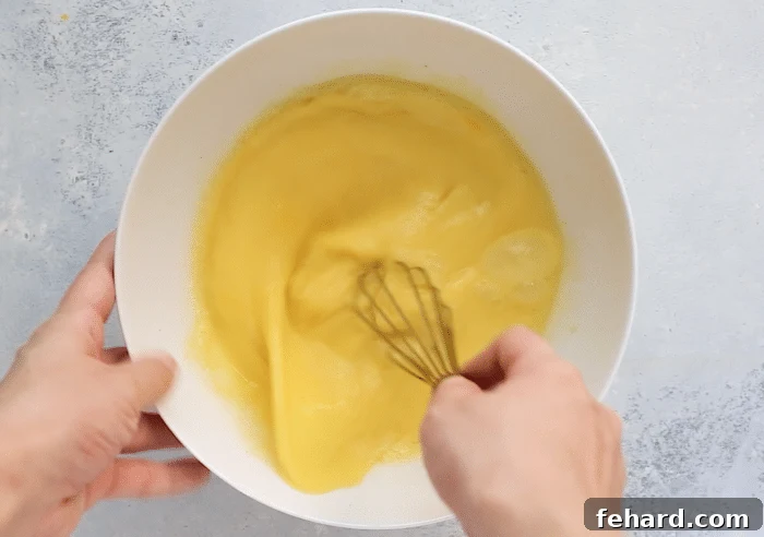 A crisp white bowl holds a perfectly whisked mixture of eggs and milk, ready to be poured into the casserole.
