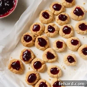 Overhead view of Cranberry Thumbprint Cookies on a baking sheet covered with parchment paper.