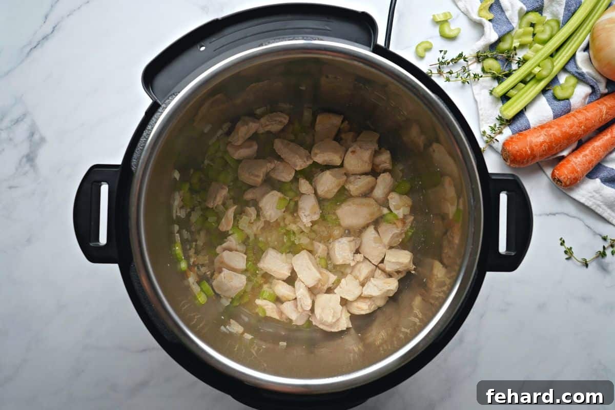 Sautéed chicken and vegetables in the Instant Pot inner pot, simmering with white wine during the deglazing process.