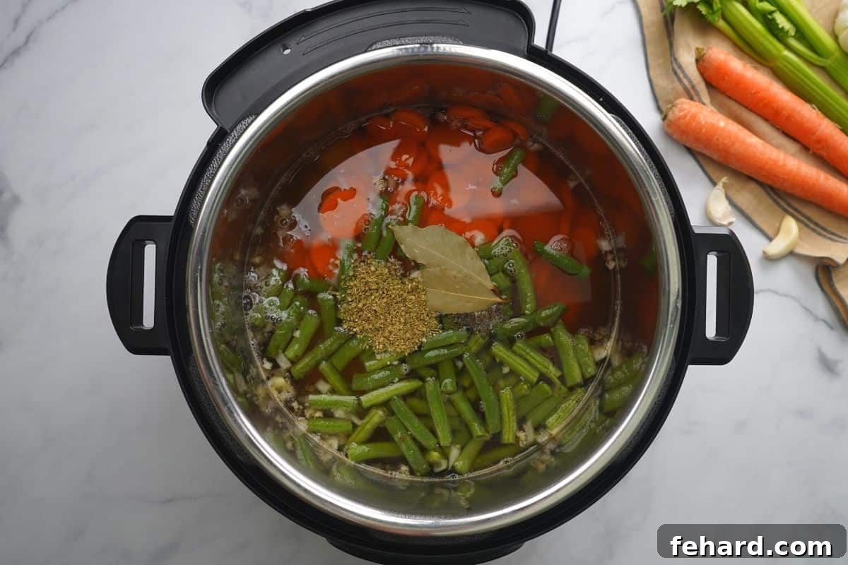Various chopped vegetables, broth, and seasonings layered neatly in the Instant Pot inner pot before cooking.