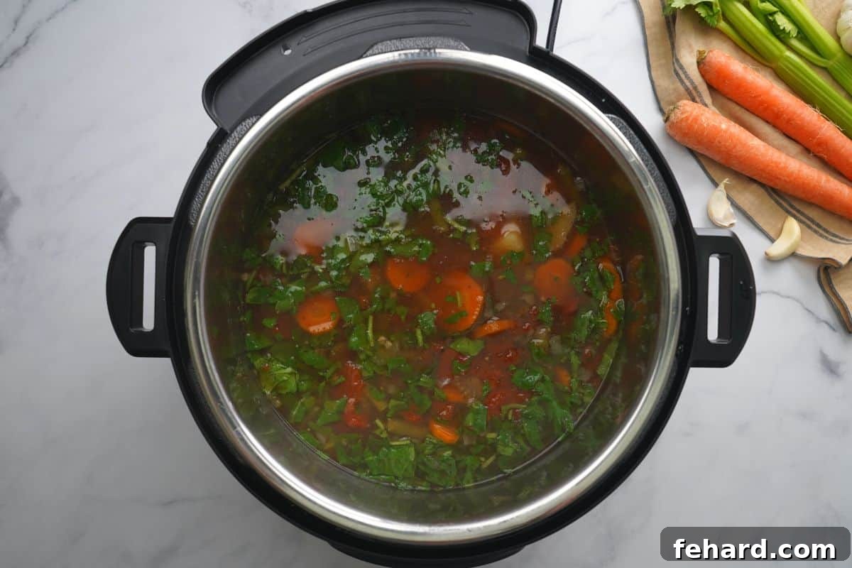 Fresh baby spinach and kale stirred into the hot vegetable soup inside the Instant Pot, wilting beautifully.