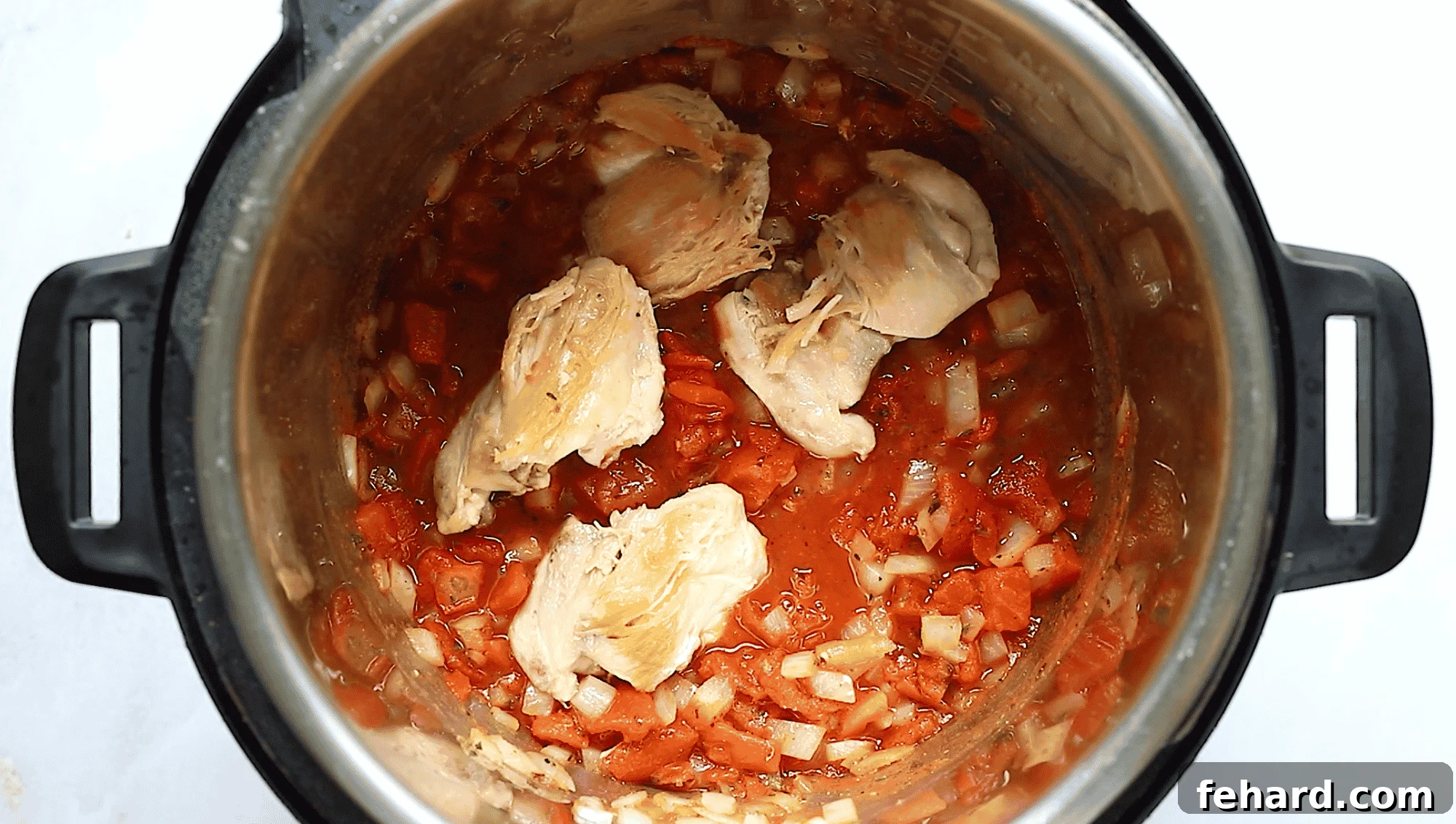 Instant Pot Mediterranean Chicken Feast 5 Overhead view of Instant Pot bowl containing chicken thighs perfectly nestled in a rich tomato sauce, ready for pressure cooking.
