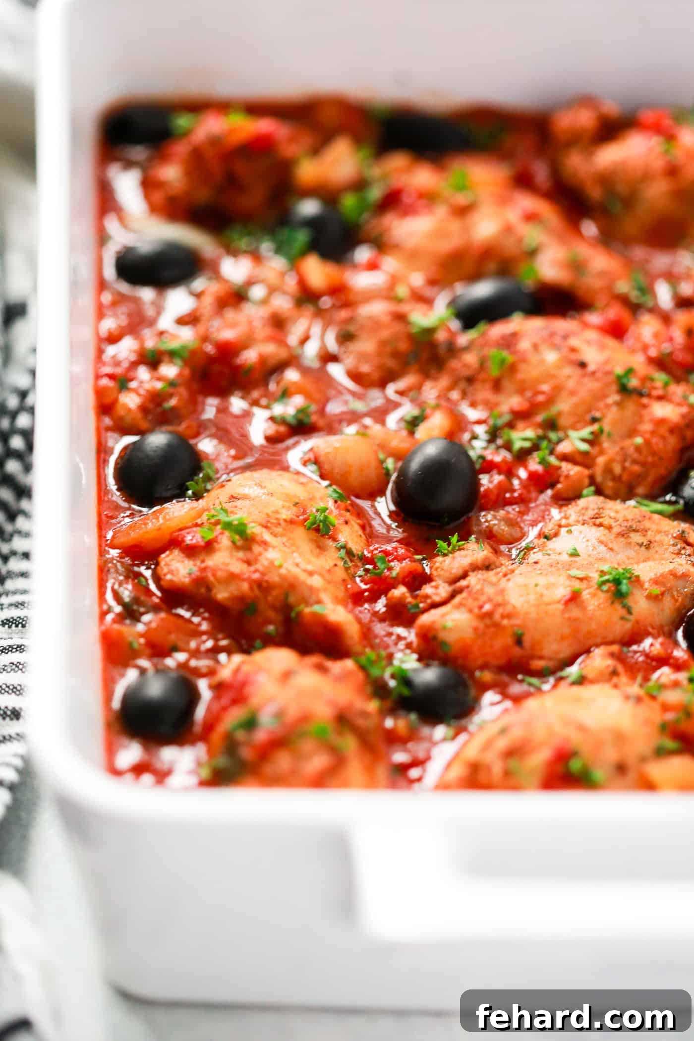 Instant Pot Mediterranean Chicken Recipe - Primavera Kitchen Delicious chicken with rich tomato sauce served in a pristine white dish, adorned with fresh herbs, ready to be served.