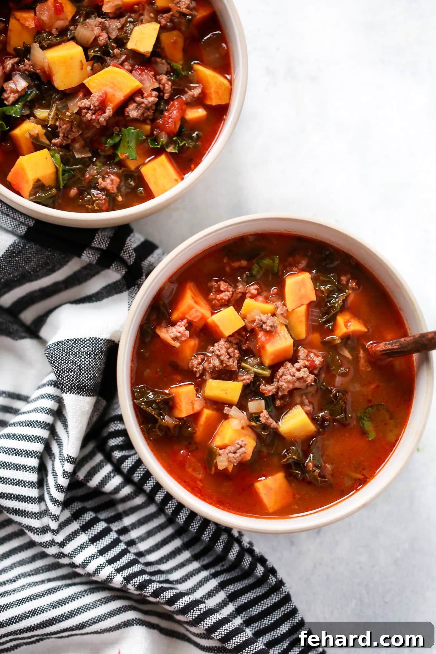 overhead view of two bowls containing Ground Beef Butternut Squash Kale Soup