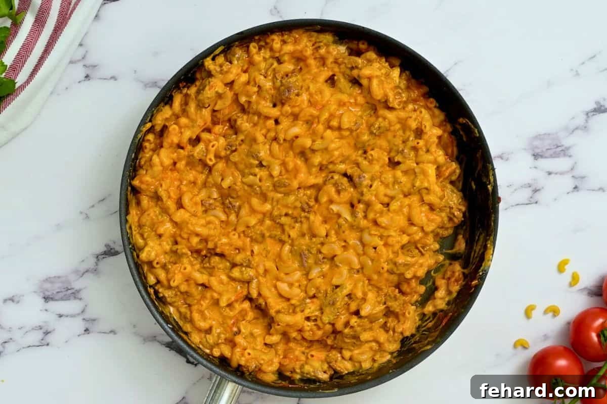 A large skillet filled with creamy, cheesy taco mac pasta, ready to be served and enjoyed by the family.