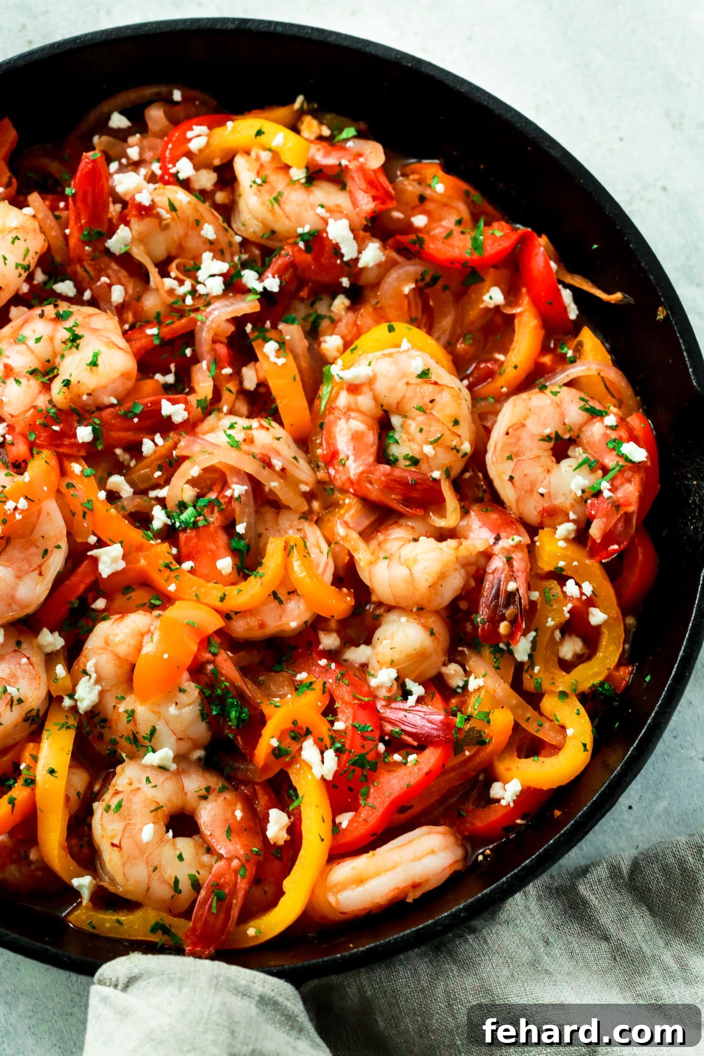 A close-up view of succulent shrimp, colorful bell peppers, and onions in a flavorful skillet, ready to be served.