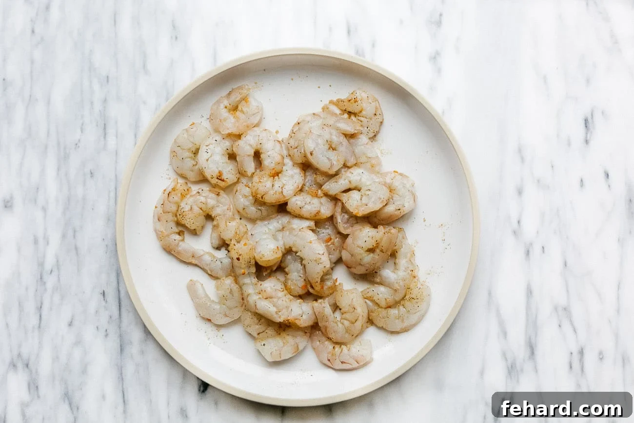 Parmesan Shrimp Perfection 3 overhead view of raw shrimp on a white plate.