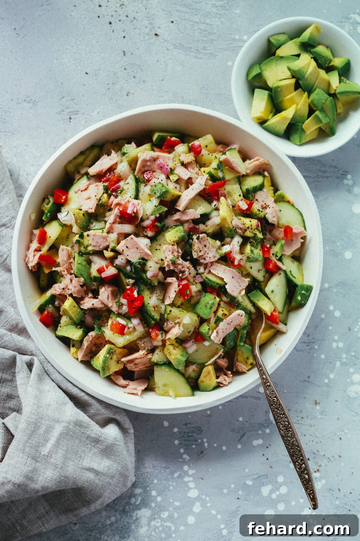 Overhead view of a super easy avocado cucumber tuna salad in a white serving bowl.