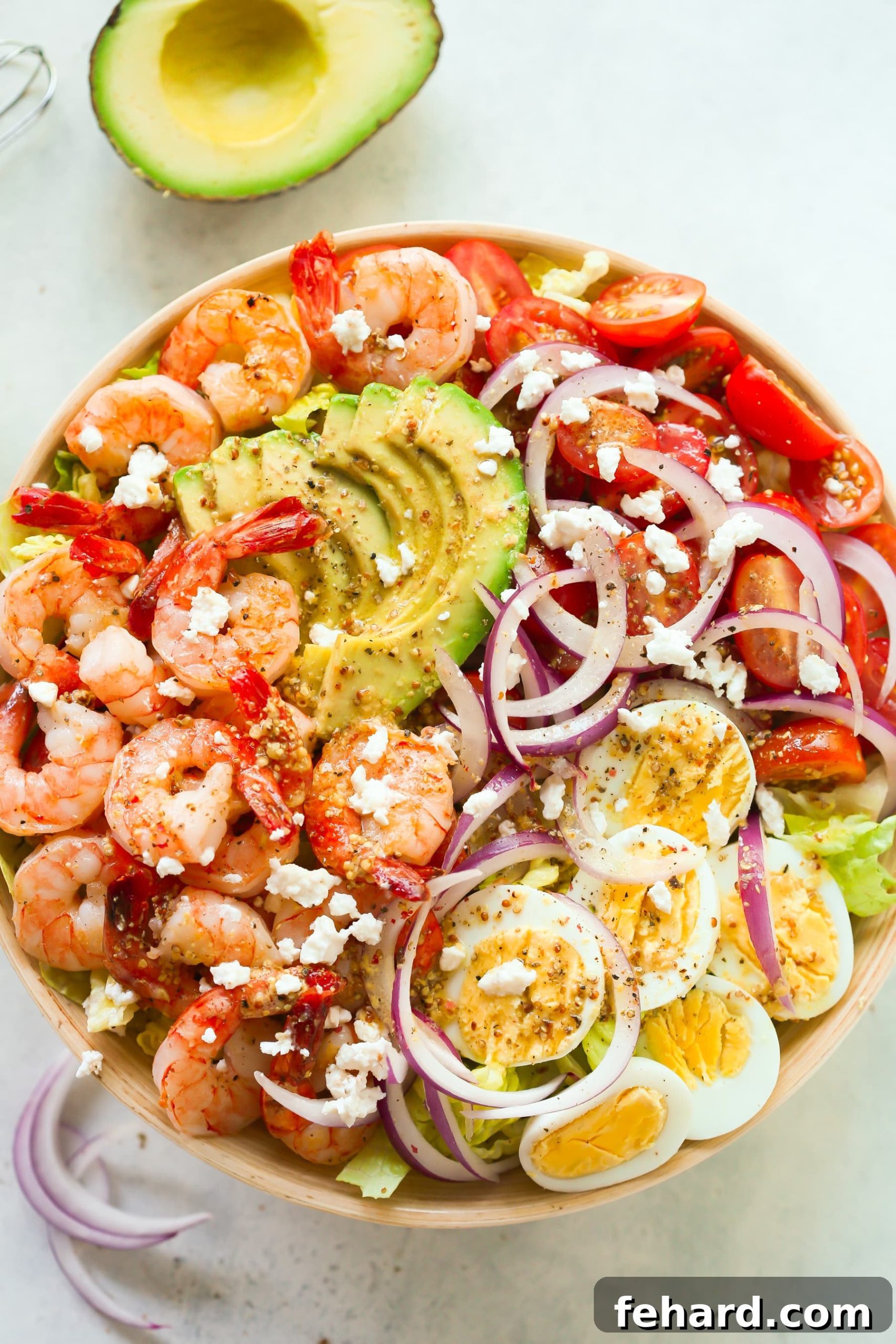 Overhead view of a beautifully arranged bowl containing shrimp, avocado, and tomato salad.