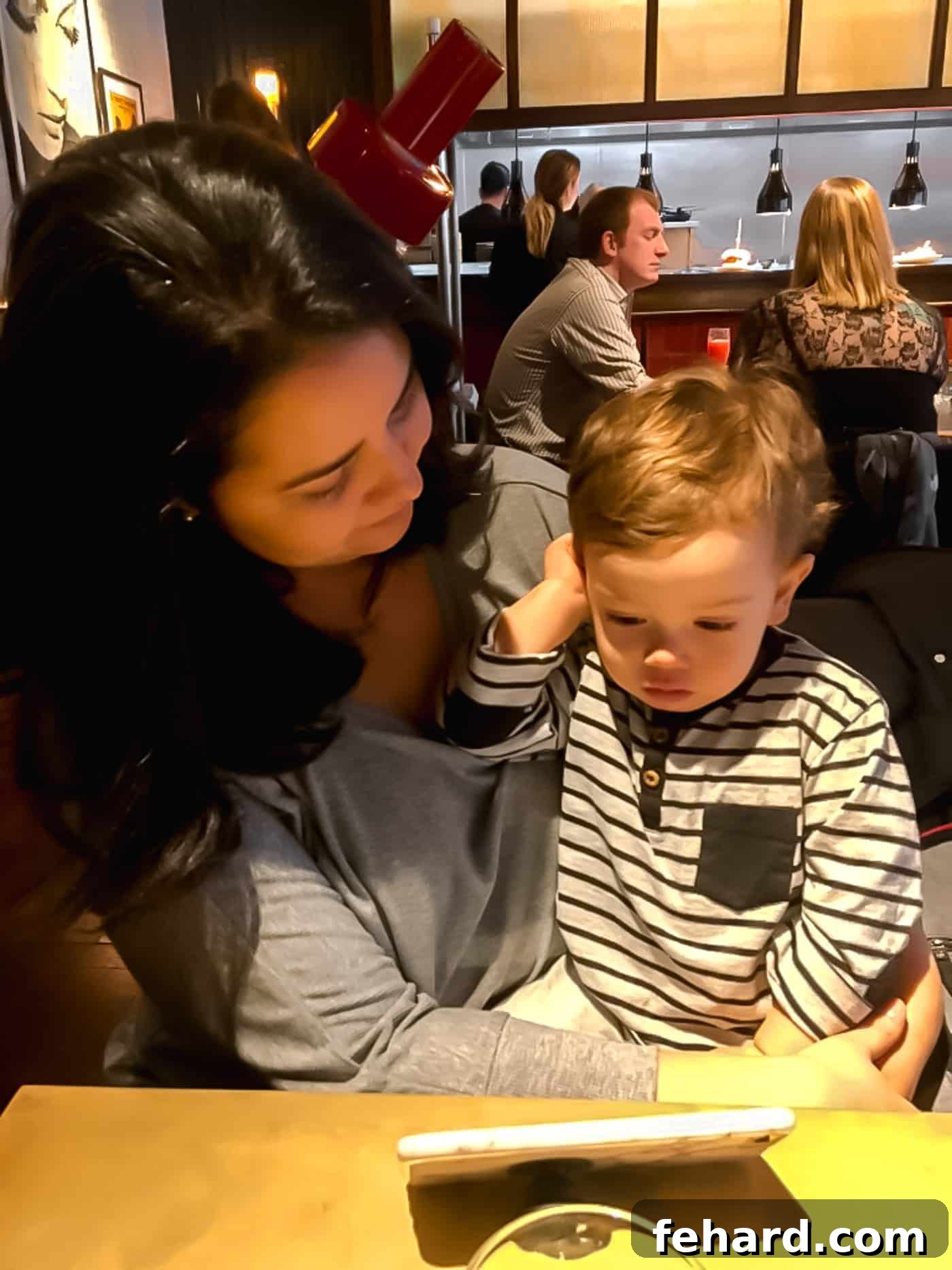 A mother holding her baby boy in a cozy restaurant setting, capturing a tender family moment