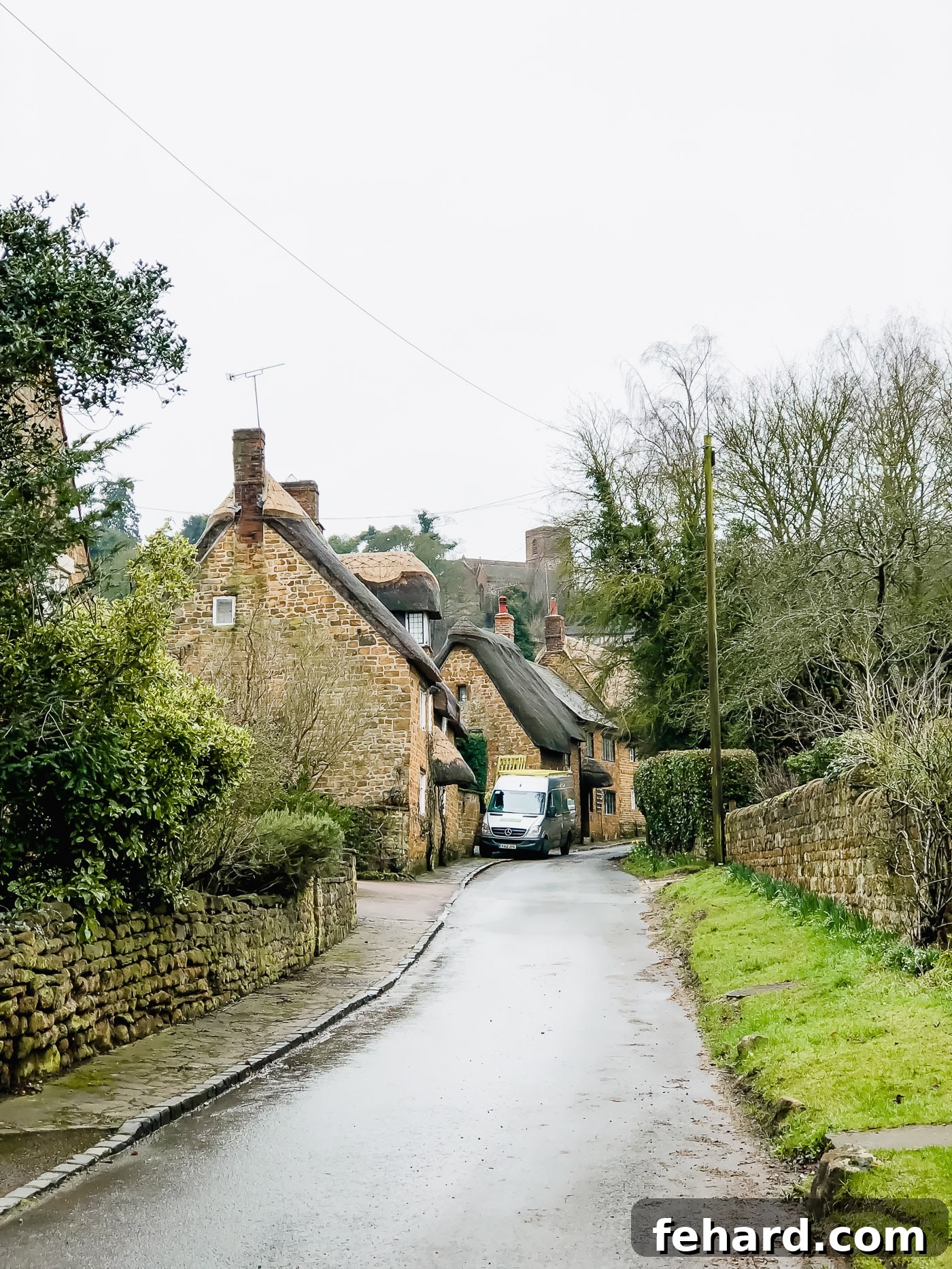 A peaceful view of a country road leading to a picturesque English cottage