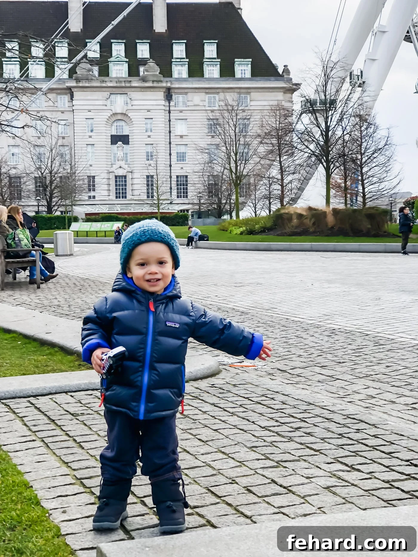 A toddler standing in front of the colossal London Eye, offering a sense of scale and wonder