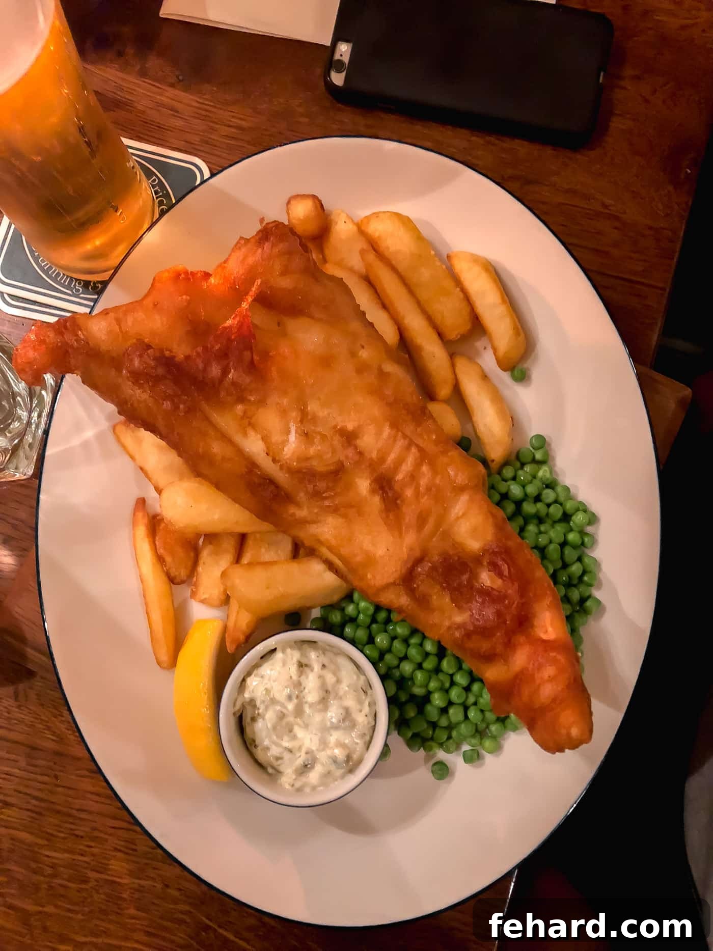 Overhead view of perfectly crispy fish and chips served on a white plate, a quintessential British meal