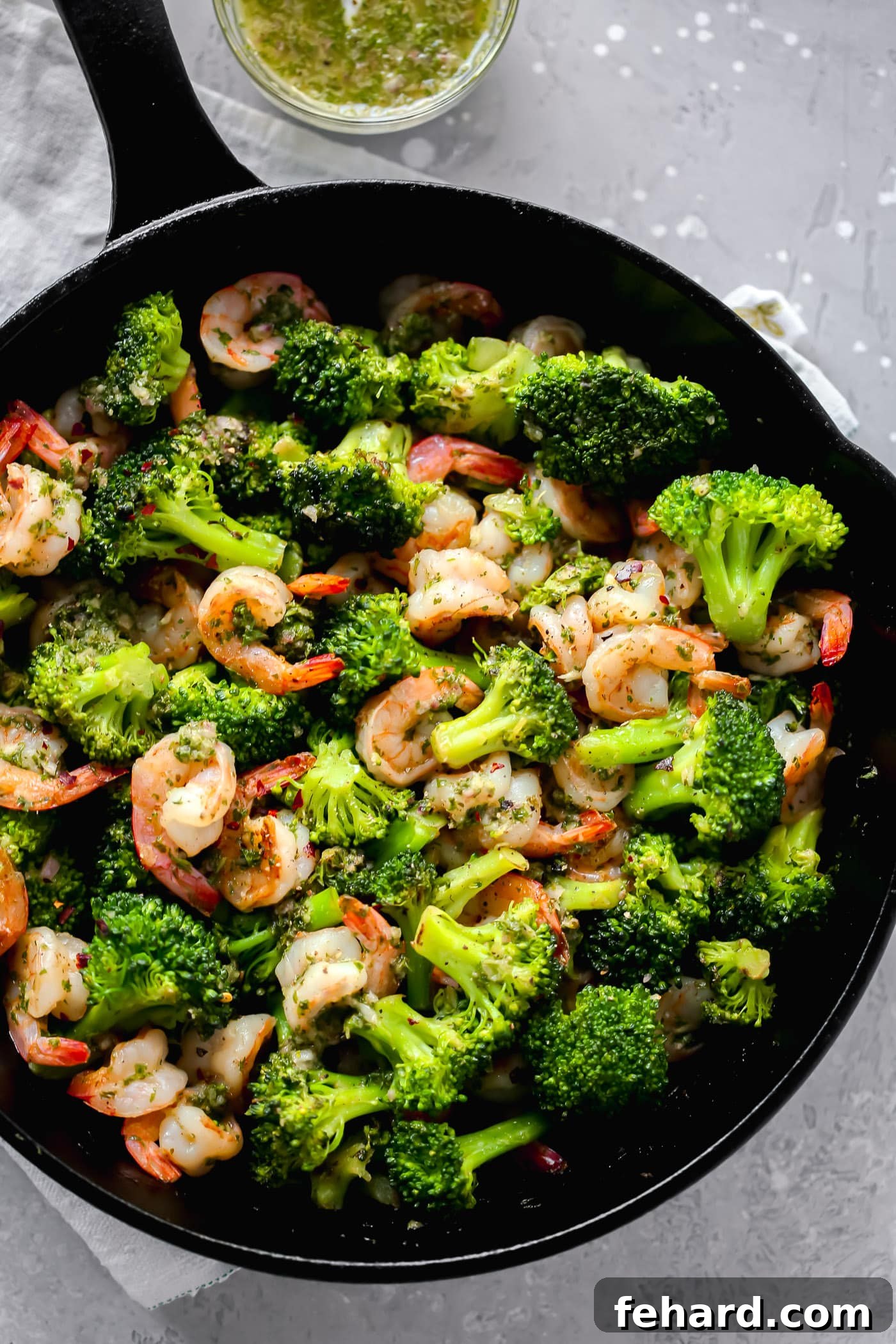 Zesty Chimichurri Prawns 6 A close-up shot of the finished chimichurri shrimp and broccoli, glistening with green sauce, served in a cast iron skillet.