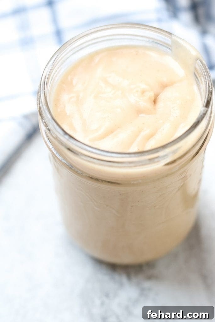 Homemade Cream of Chicken Soup Clear glass jar filled with thick condensed cream of chicken soup from scratch, ready for use.