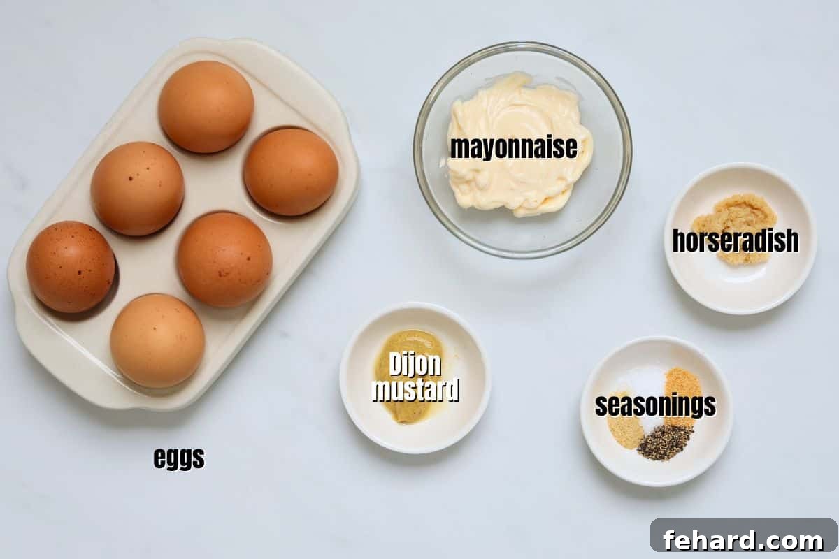 Easy Egg Salad Ingredients Hard-boiled eggs, mayonnaise, Dijon mustard, prepared horseradish, garlic powder, onion powder, salt, and pepper arranged on a kitchen counter, ready for making egg salad.