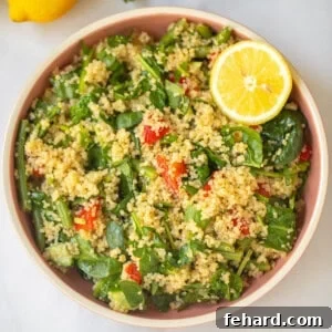 Bowl of quinoa spinach salad with lemon wedges and fresh green beans.