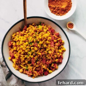 Overhead photo of a bowl of golden cauliflower rice, garnished with fresh chives.