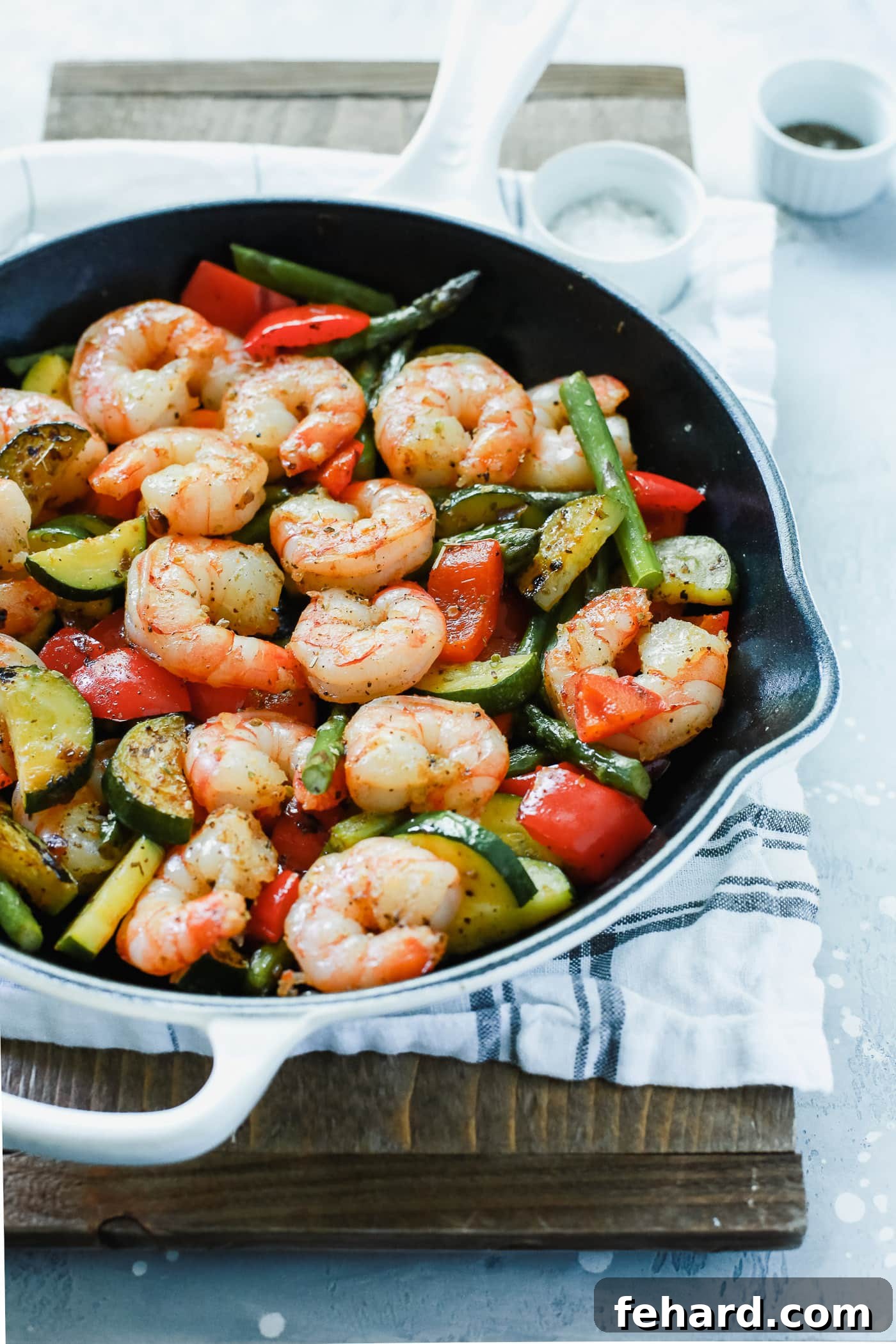 Plump shrimp, tender zucchini, crisp asparagus, and vibrant red bell peppers sizzling in a rustic cast-iron skillet.