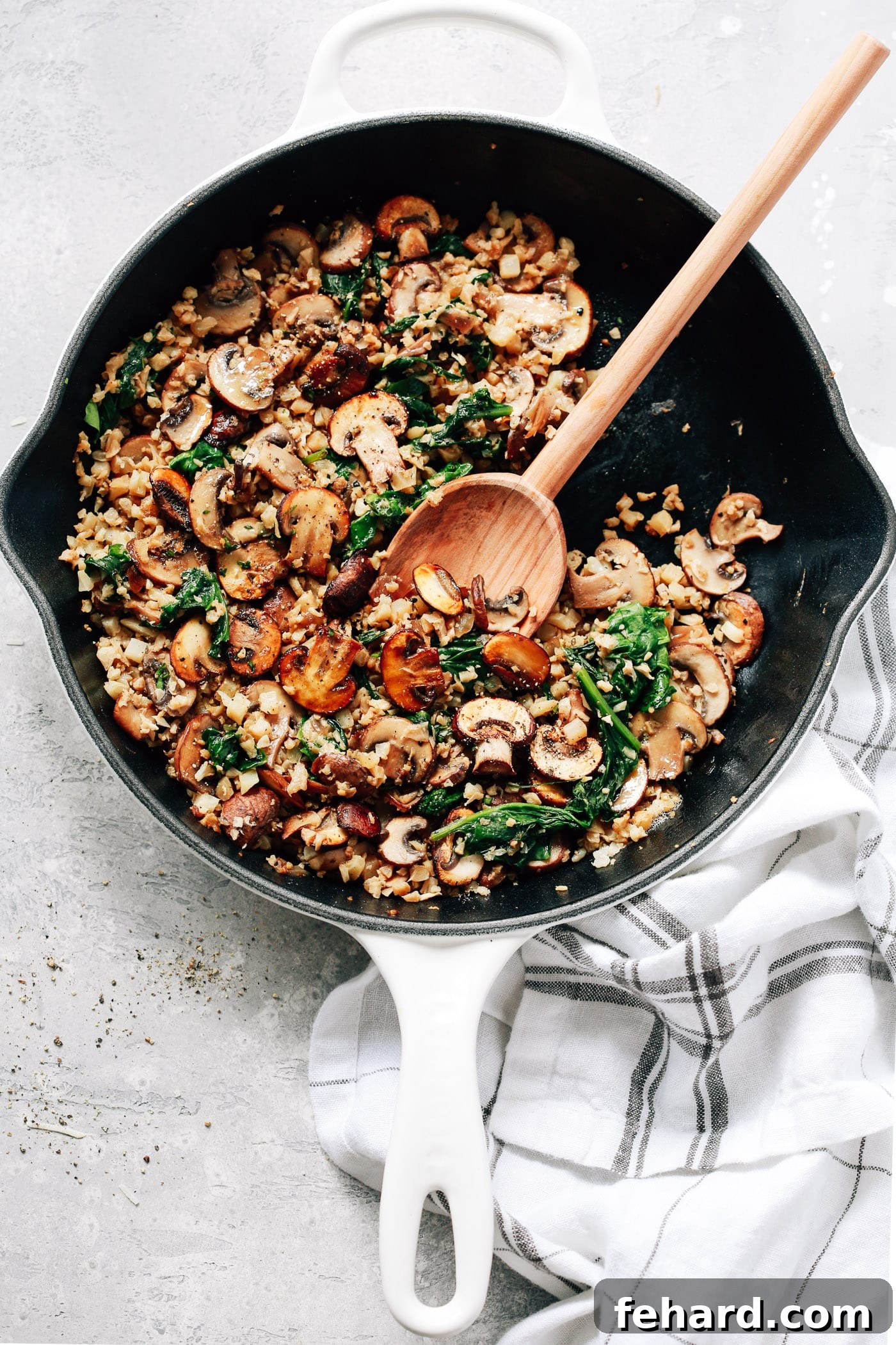 An inviting overhead view of a pristine white skillet, showcasing a perfectly cooked blend of earthy mushrooms and fluffy cauliflower rice.
