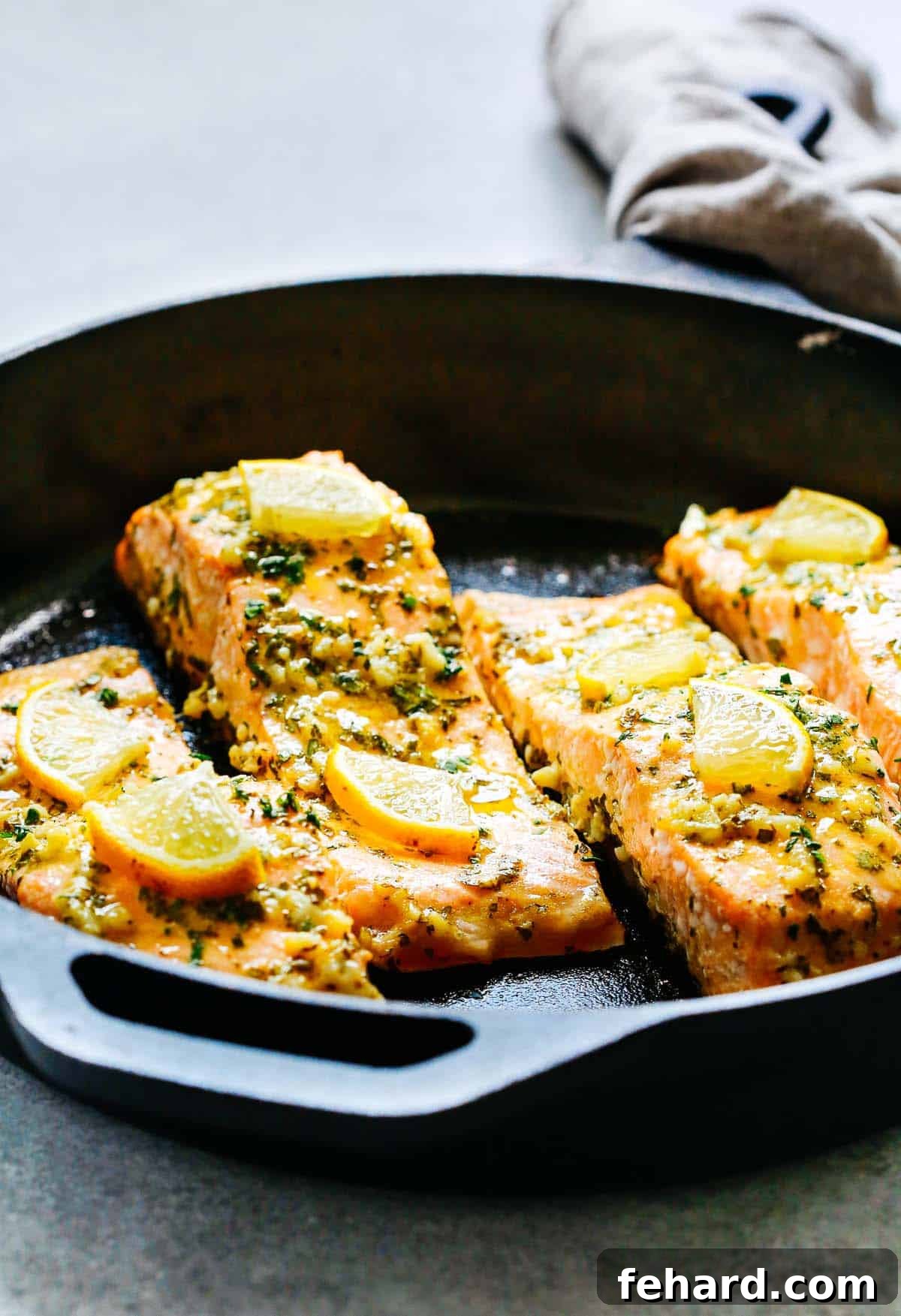 Cooked Dijon mustard salmon topped with fresh lemon slices in a large cast iron skillet, ready for serving.
