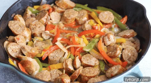 Sausage and peppers simmering until liquid evaporates.
