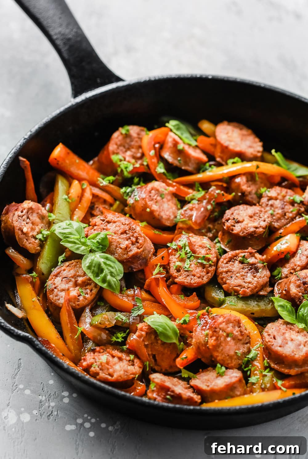 Italian Sausage, Onions and Peppers Skillet in a close-up shot, garnished with fresh herbs, ready for serving.