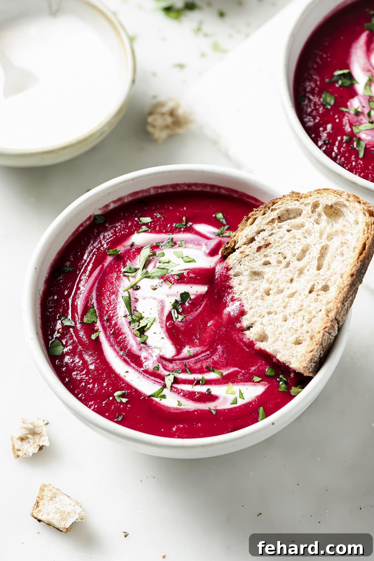 Vibrant Beetroot Soup 7 Beet soup in a white bowl with garnish and a slice of bread.