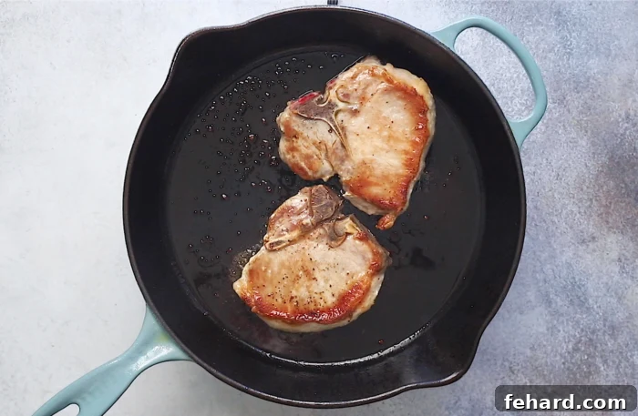 searing the pork chops in a cast iron skillet to achieve a golden crust