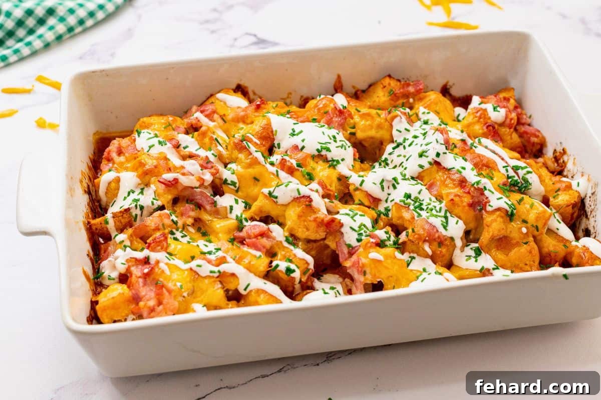 Delicious Buffalo Chicken Casserole baked to perfection, showing layers of chicken, crispy potatoes, melted cheese, and bacon, garnished with chives and a side of ranch.
