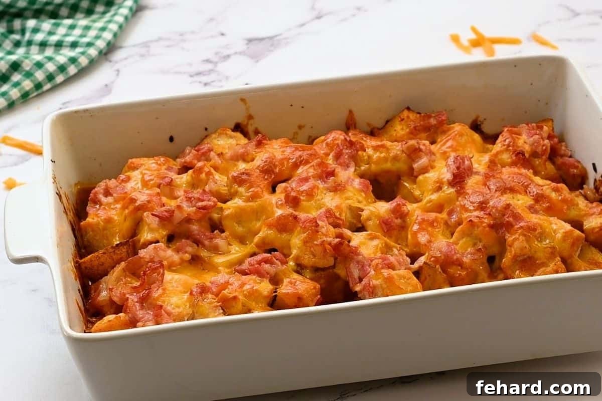 A freshly baked Buffalo Chicken Casserole, bubbly with melted cheese, crispy bacon, and golden potatoes, garnished with fresh chives, ready to be served.