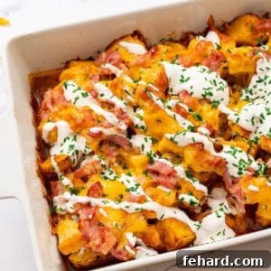 Crispy cubed potatoes topped with buffalo chicken, diced bacon, and shredded cheddar in a casserole dish to make Buffalo Chicken Casserole.