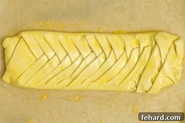 Braided Cream Cheese Danish on parchment paper brushed with egg wash.