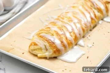 Glazed puff pastry cream cheese danish on baking sheet.