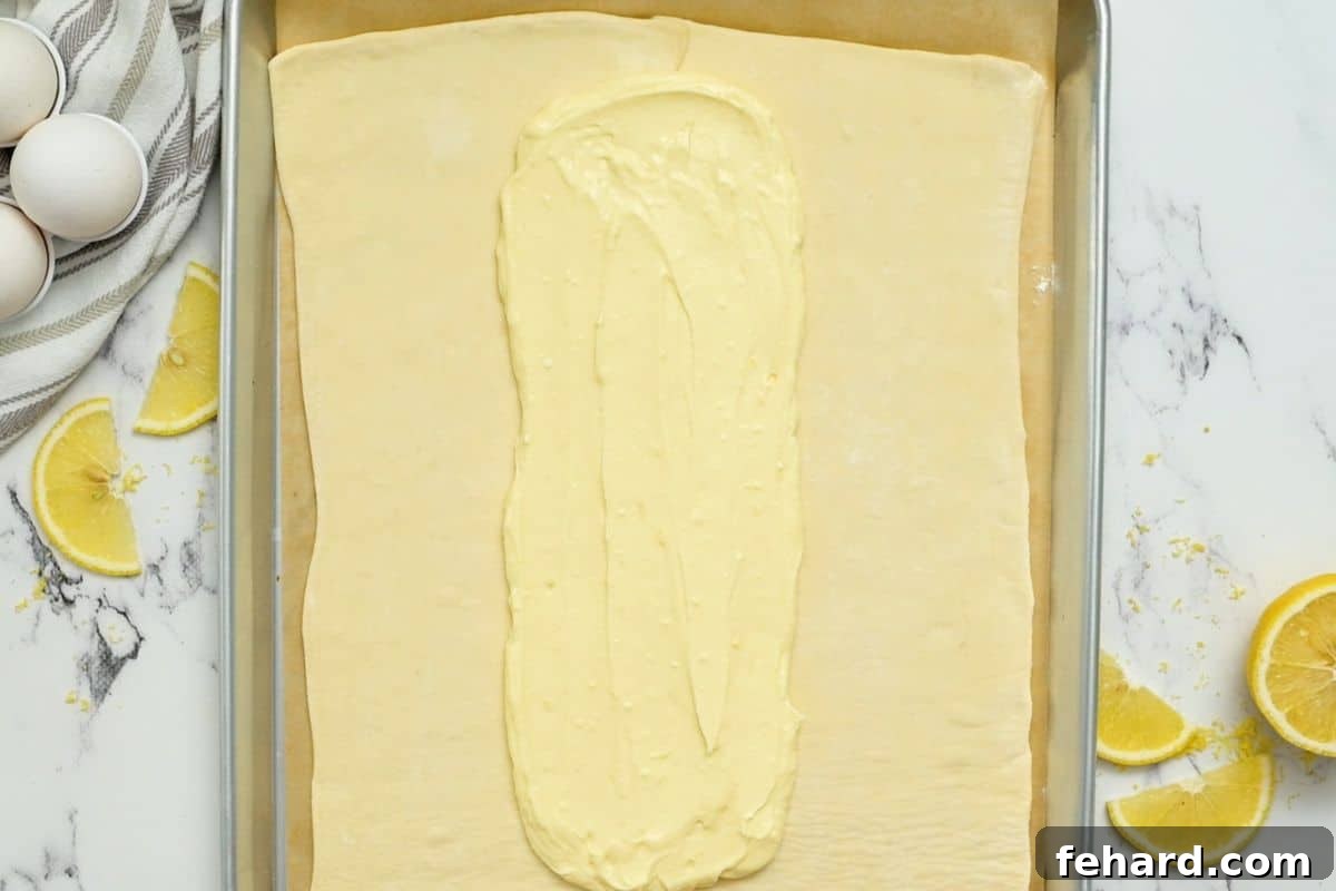 Cream Cheese Filling perfectly spread down the center of a rectangular puff pastry sheet, ready for braiding.