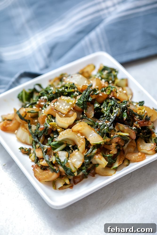 Stir Fried Bok Choy on white plate topped with sesame seeds.