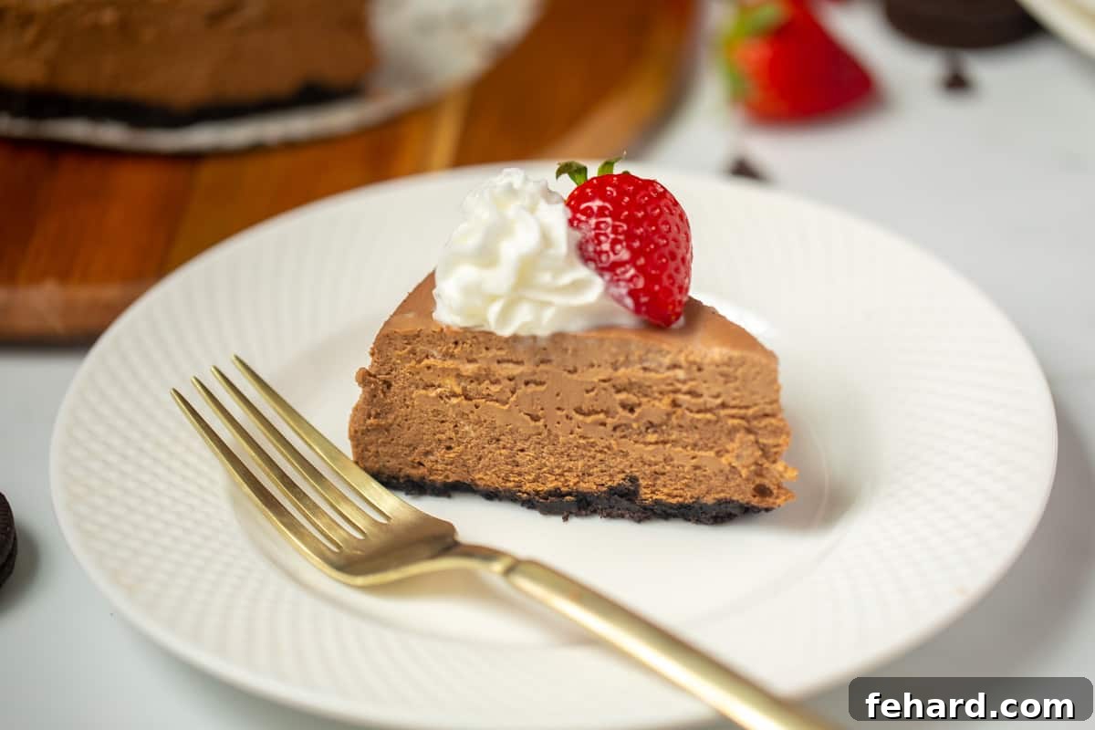 Chocolate Cheesecake Instant Pot A delectable slice of Instant Pot chocolate cheesecake on a white plate, elegantly garnished with whipped cream and a fresh strawberry, ready to be enjoyed.